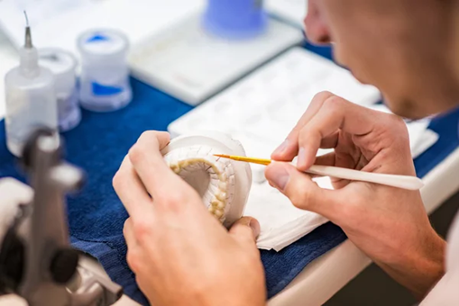 A maxillofacial prosthodontist prepares a set of dentures.